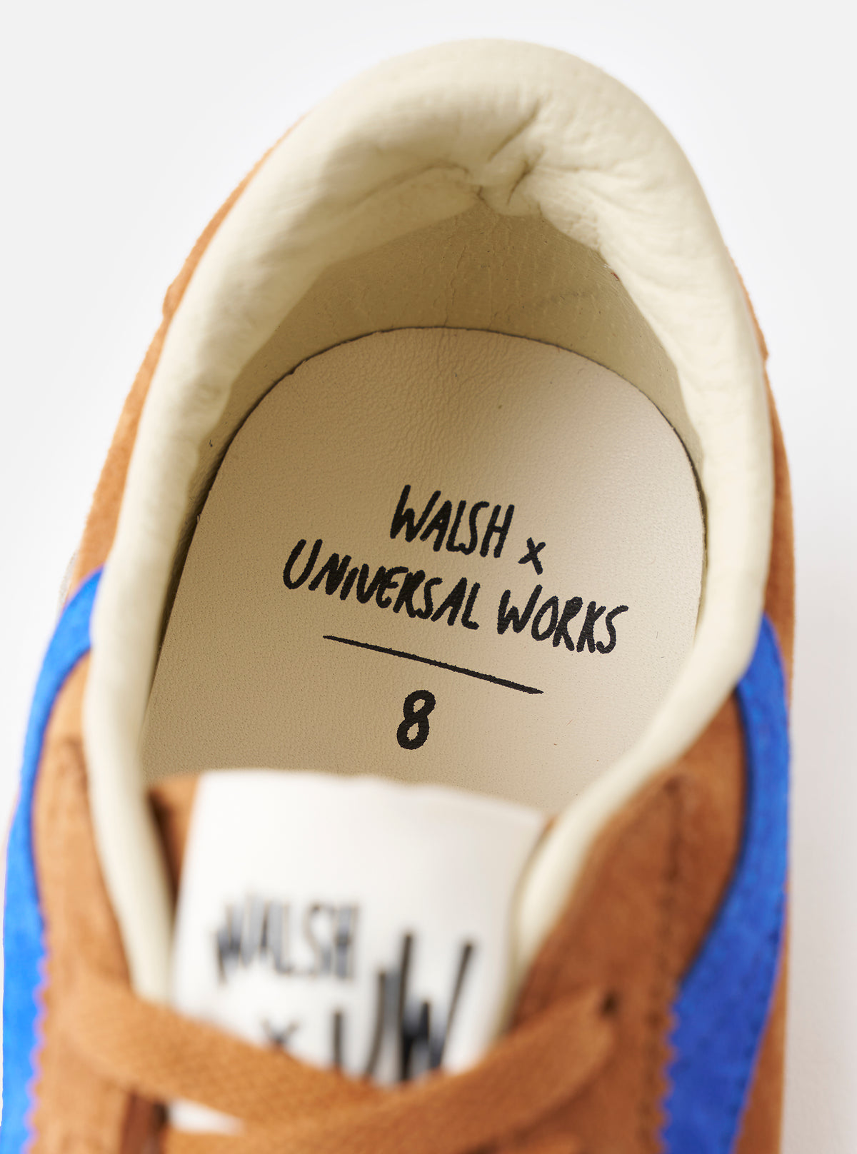 Detailed close-up shot of the Walsh x Universal Works Cob in Tan Leather, highlighting the supple leather texture, reinforced eyelet stay, and clean side stitching against an off-white background.