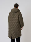 Back view of a model wearing the TAION x Universal Works Reversible Dark Olive Military Line Parka. The quilted parka has a hood and is on a white background.