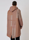Back view of a model wearing the TAION x Universal Works Reversible Dark Olive Military Line Parka. The parka is brown and tan plaid. Shot against a white backdrop.