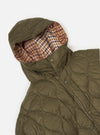 Close-up of the TAION x Universal Works Reversible Dark Olive Military Line Parka, showcasing its quilted texture and the reversible houndstooth patterned hood lining on a white background.