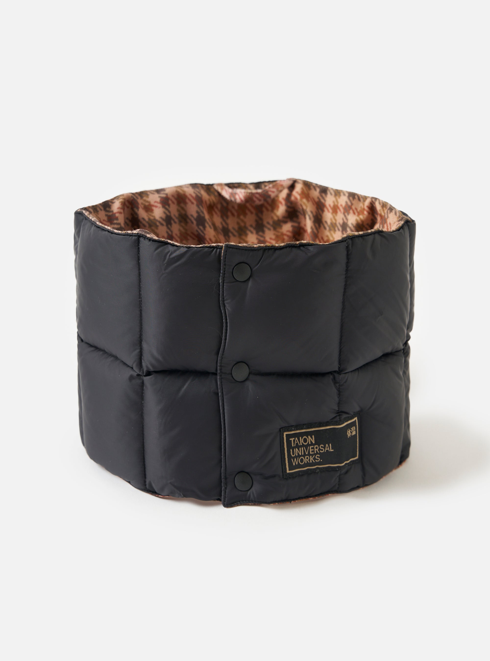 The TAION x Universal Works Reversible Black Military Line Neck Warmer on a white background. It's black with a houndstooth pattern on the inside and has a branded tag.