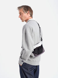 A model showcases the F/CE.® White Nylon Cordura Sil Sacoche. The bag features white, black, and gray nylon. Shot in a studio with a white background.