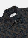 Close-up of the Navy Mitla Print Cotton Rose Bowl Jacket. The jacket features a navy and brown geometric print, a full zip, and is made of cotton. Shot on a white background.