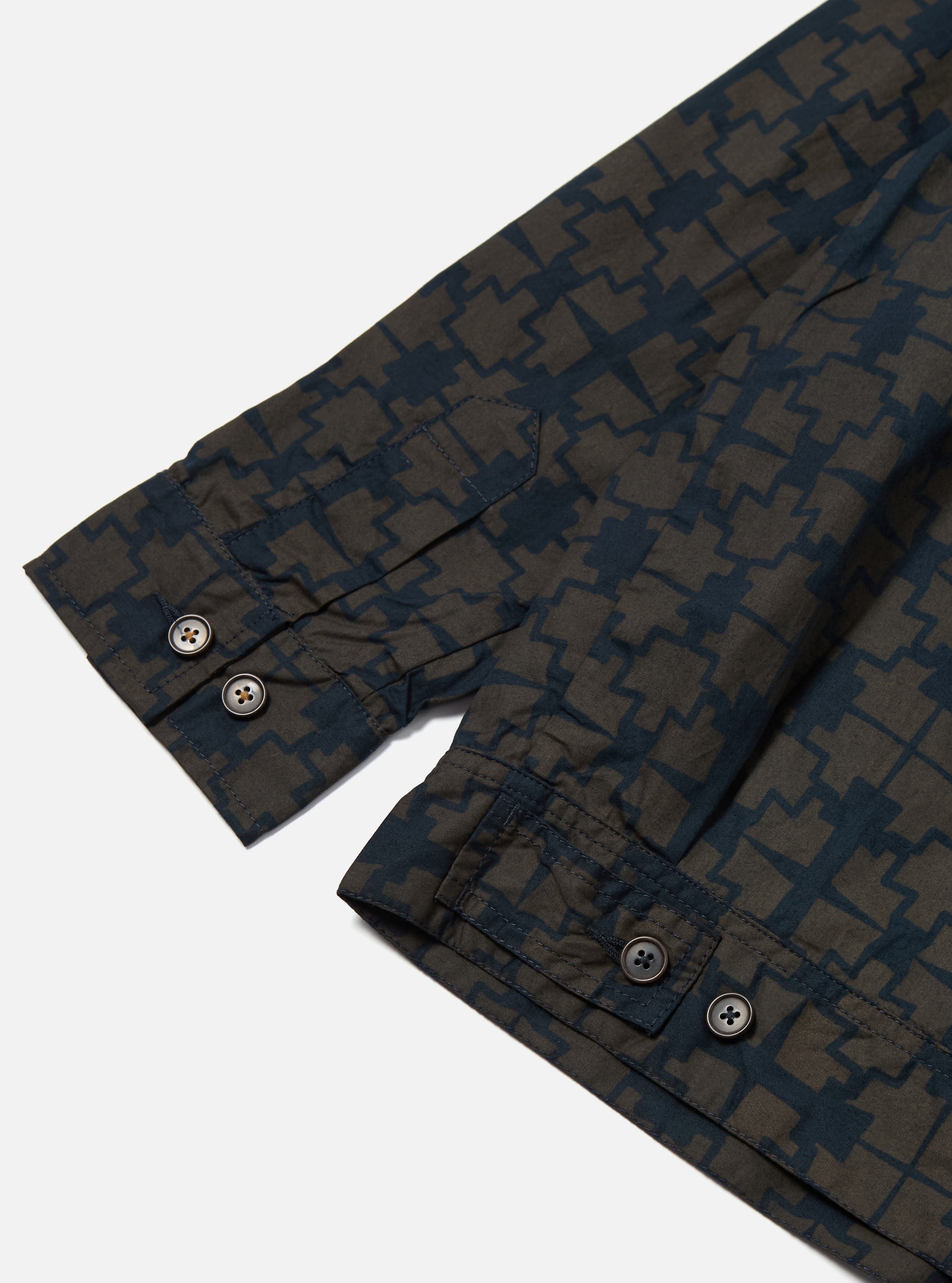 Close-up of the Navy Mitla Print Cotton Rose Bowl Jacket sleeve. The jacket has a navy and brown geometric print and brown buttons. Shot on a white background.