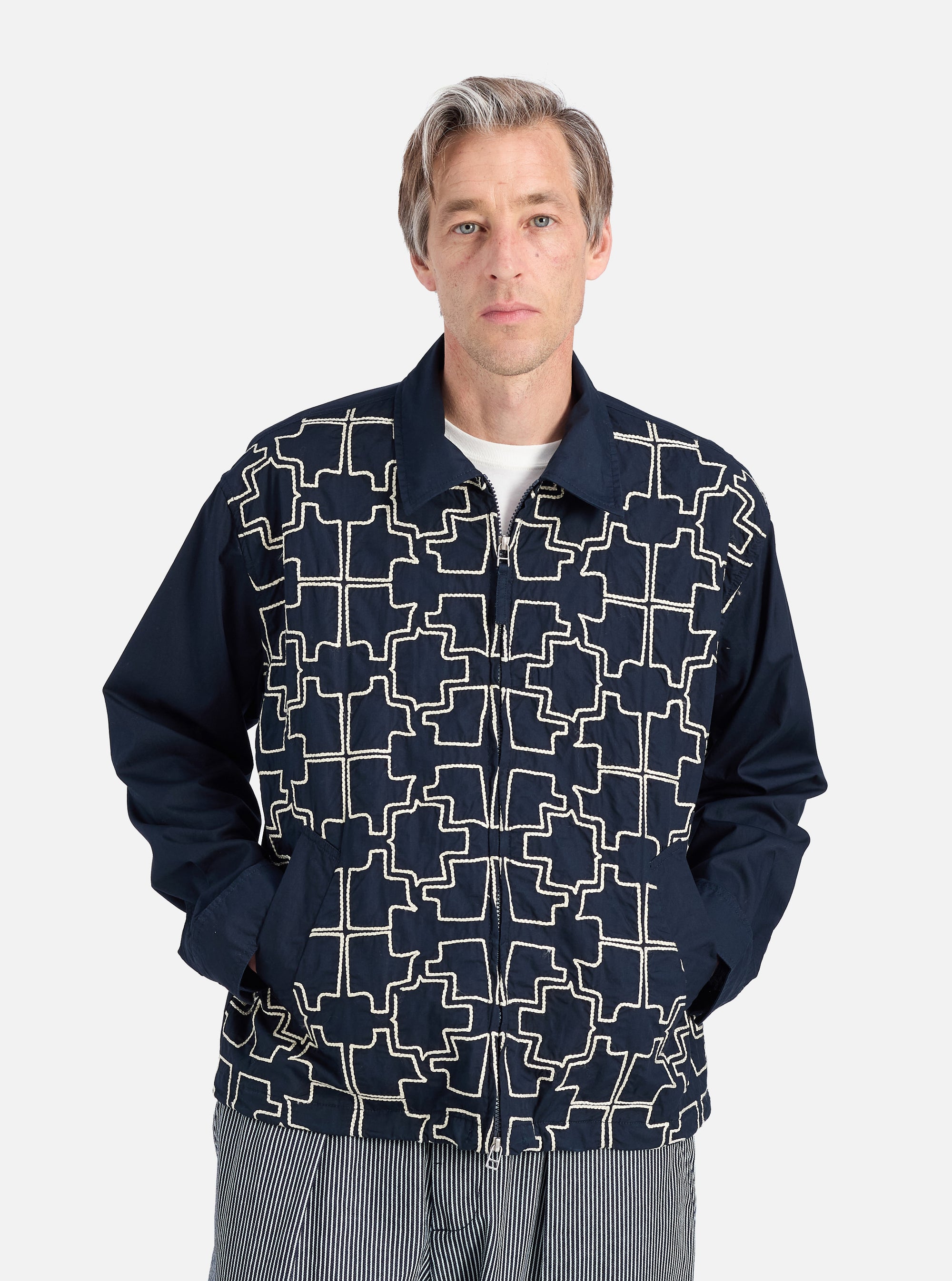 A model wears the Navy Mitla Broadcloth Club Jacket against a white backdrop. The jacket is navy with a white geometric pattern. It has a relaxed fit.