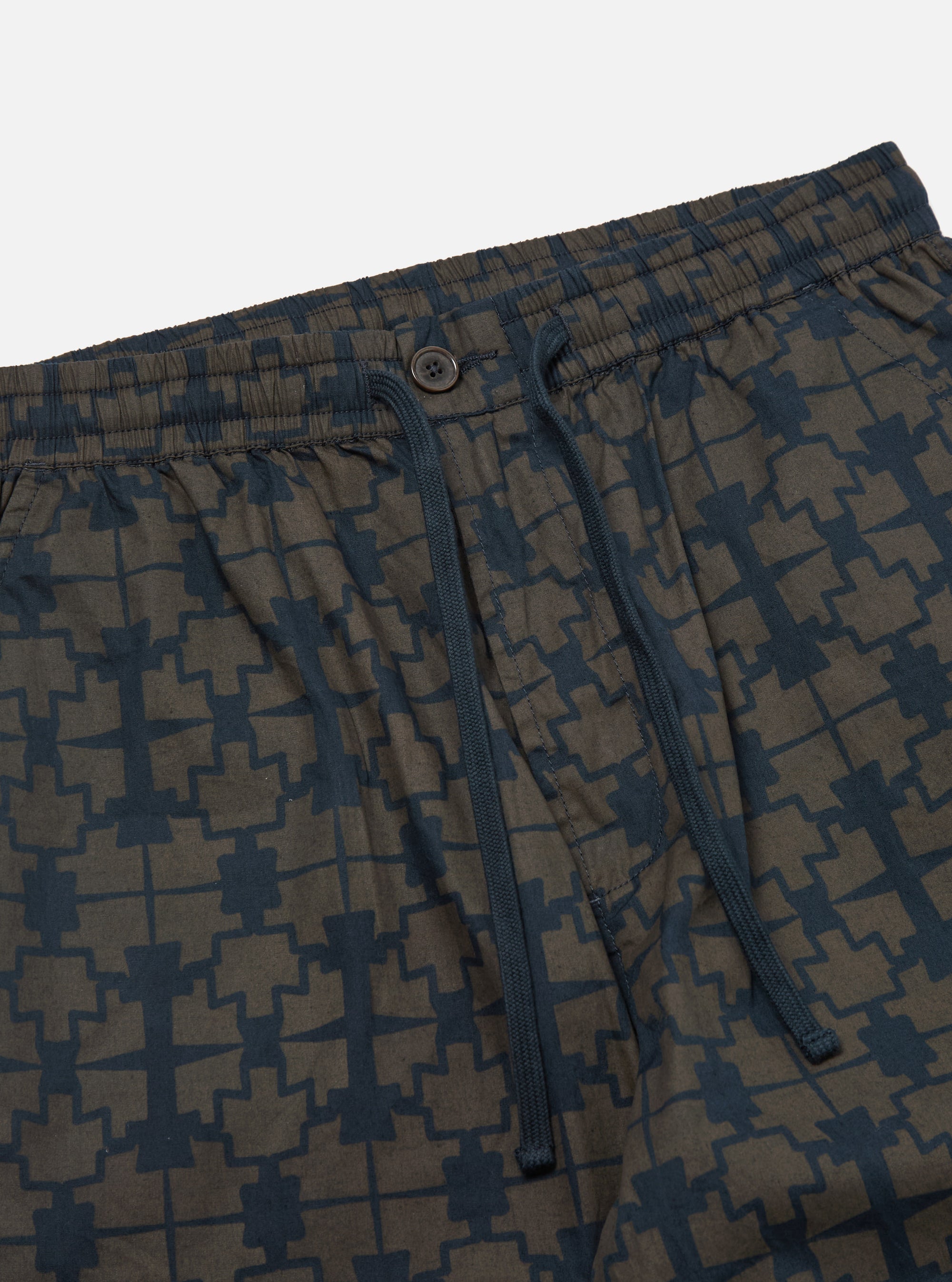 Close-up of the Navy Mitla Print Cotton Hi Water Trouser on a white background. The trousers have a navy blue geometric print and a button closure.