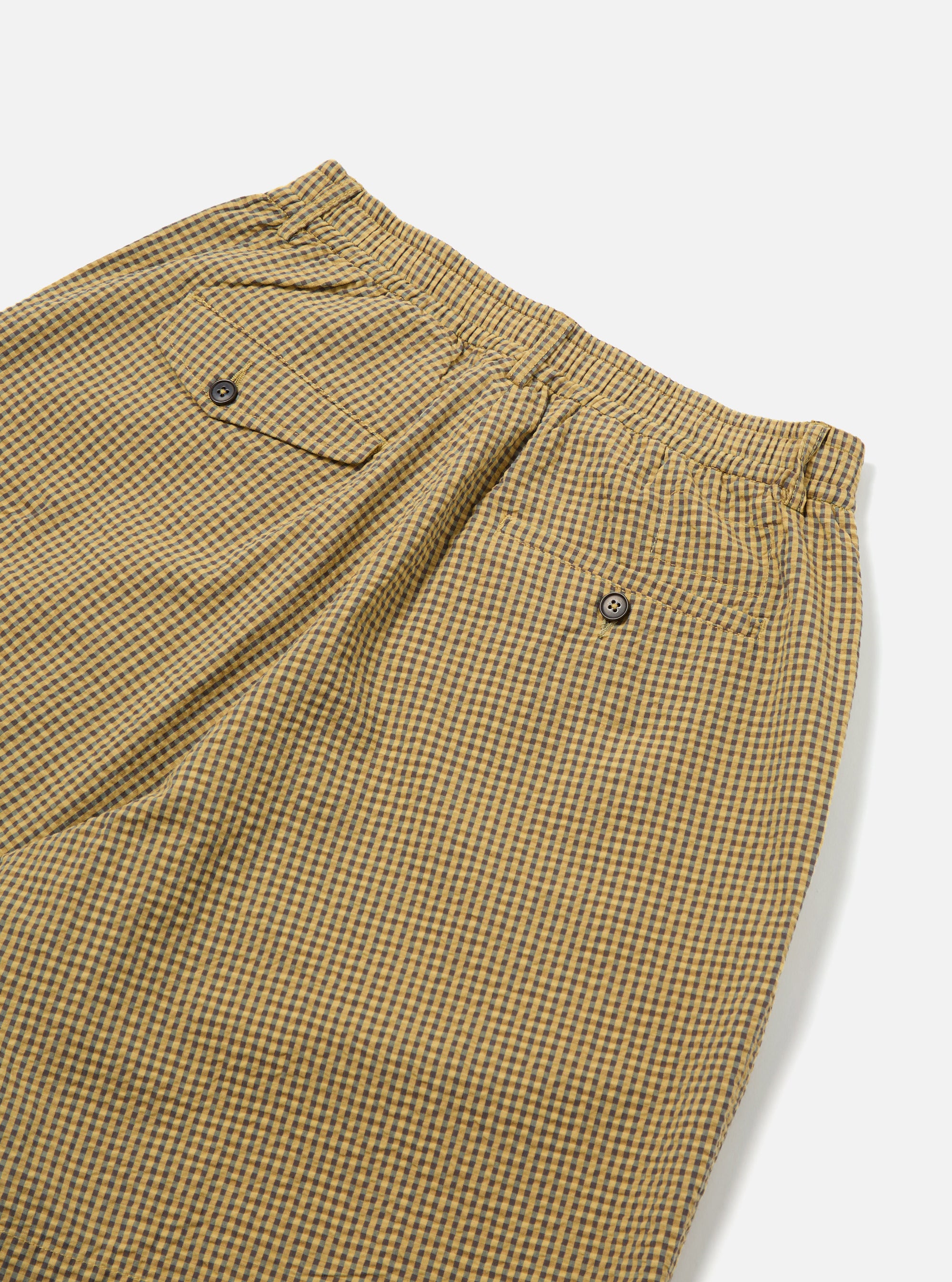 Close-up of the Yellow Japanese Seersucker Pleated Track Short on a white background. The shorts have a yellow and brown checkered pattern and a pleated design.