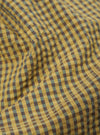 Close-up of the Yellow Japanese Seersucker Pleated Track Short fabric. The material is a yellow and blue plaid with a textured seersucker feel.