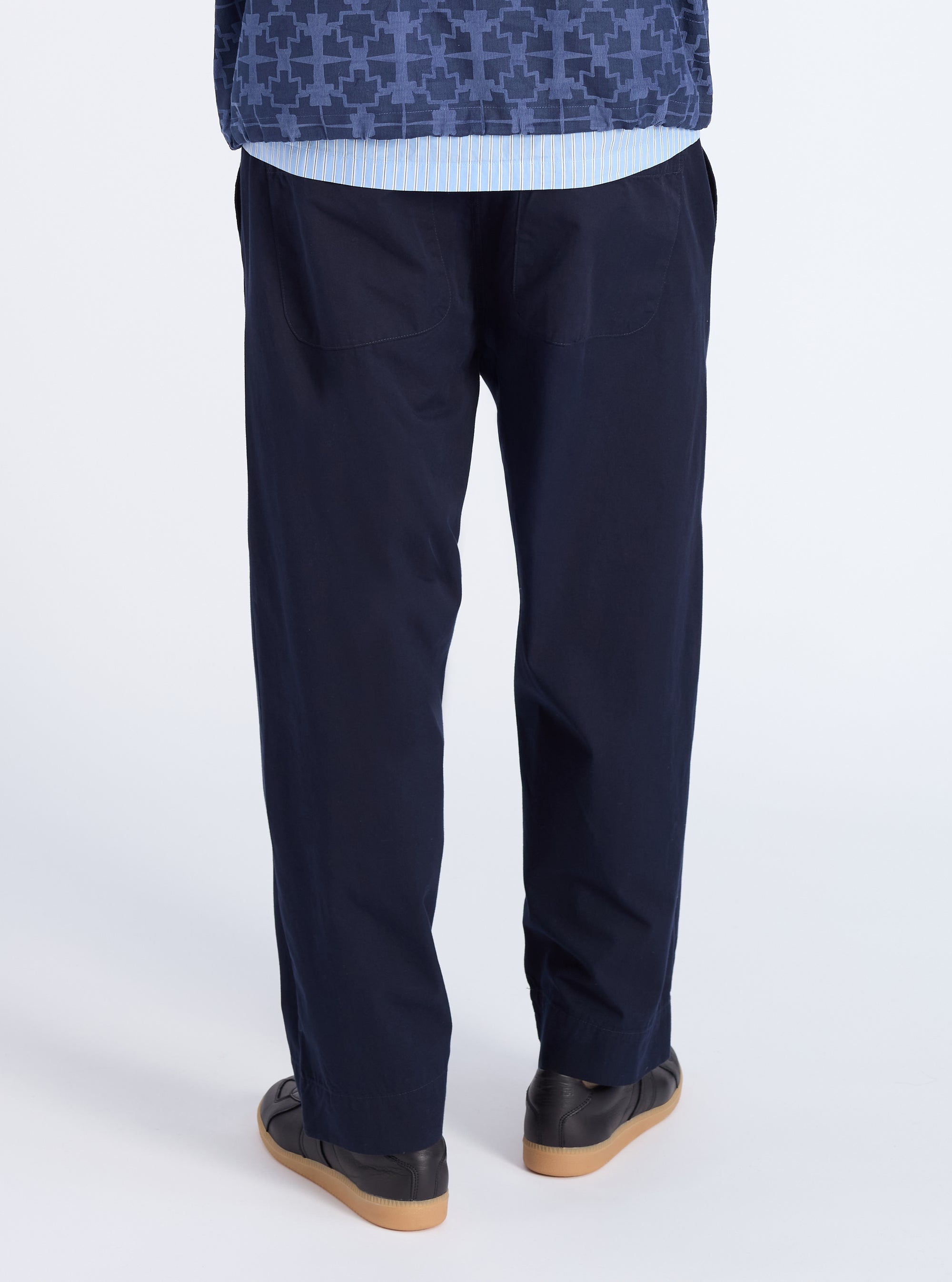 Back view of a model wearing the Navy Military Cotton Judo Pant. The pants are a loose fit and made of cotton. The background is a clean white studio.