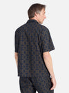 A man wears the Navy Mitla Print Cotton Road Shirt, a short-sleeved button-down with a geometric pattern. Shot in a studio against a white backdrop.