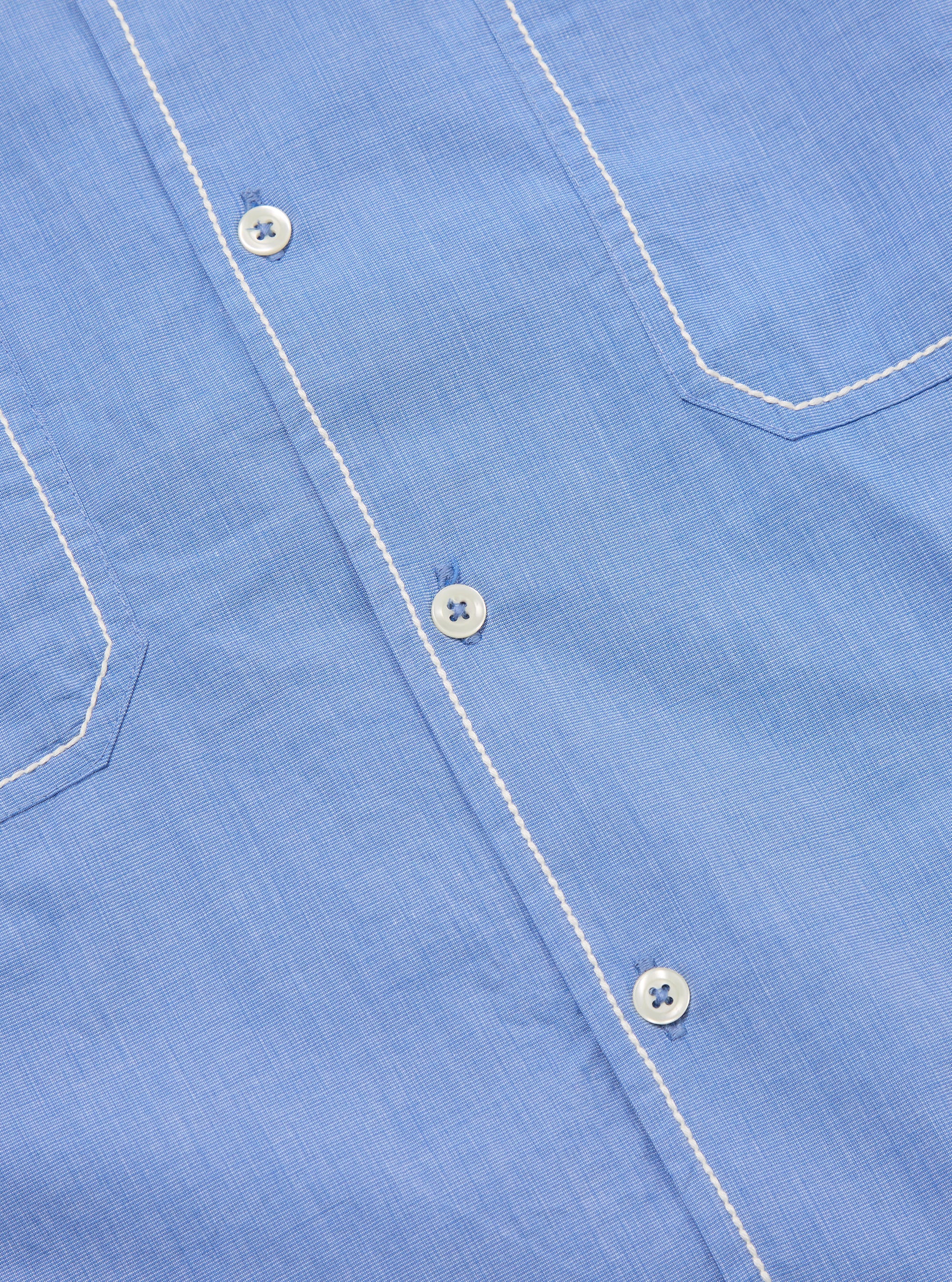Close-up of the Blue End On End Cotton Utility SS Shirt. Shows the light blue cotton fabric, white buttons, and white stitching on the pockets and placket. 