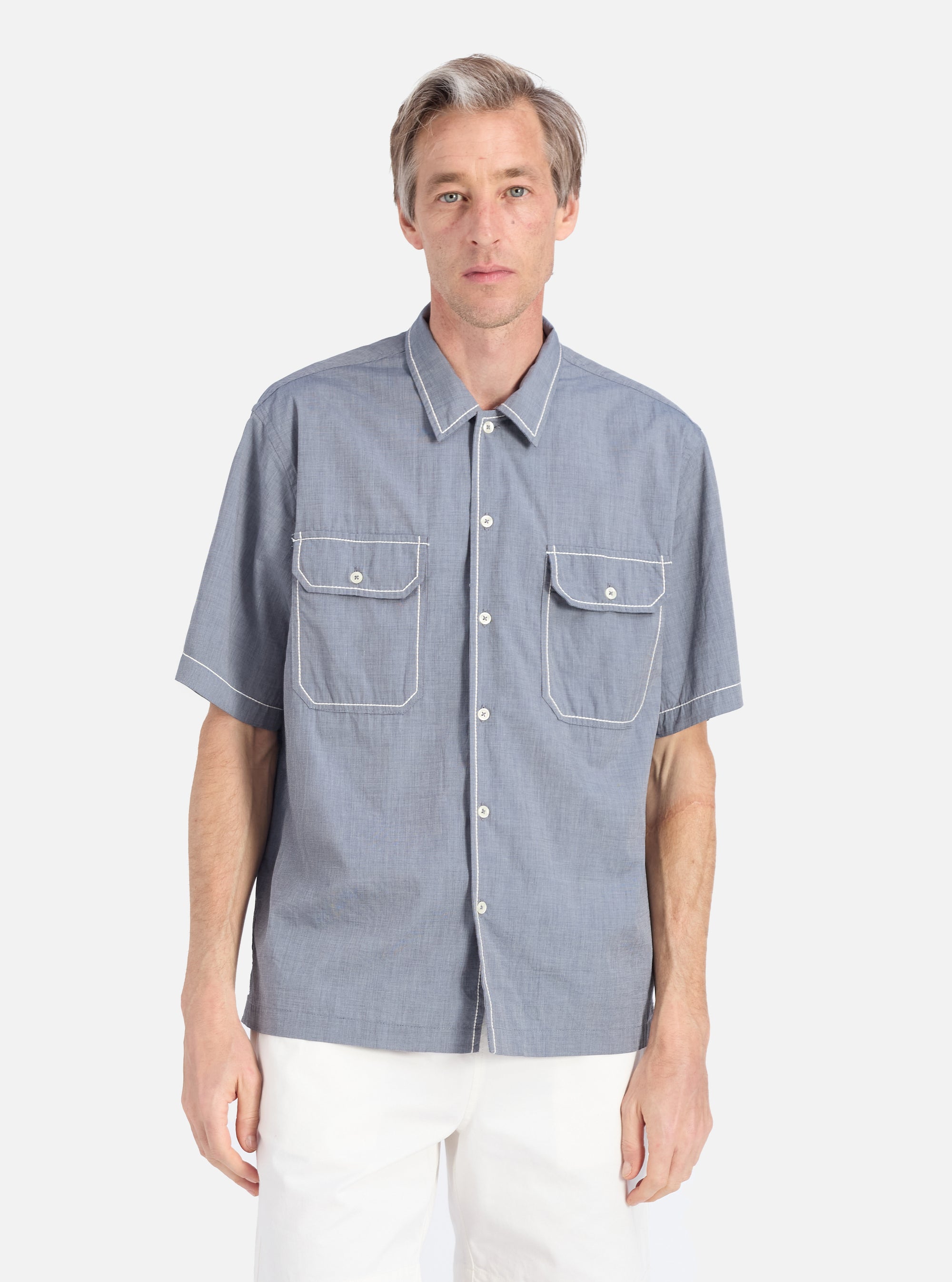 A model wears the Grey End On End Cotton Utility SS Shirt. The shirt is grey with white stitching on the pockets and collar. The background is a clean, bright white.