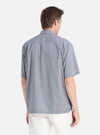 A man stands against a white backdrop, showcasing the back of the Grey End On End Cotton Utility SS Shirt. The shirt is paired with white pants.