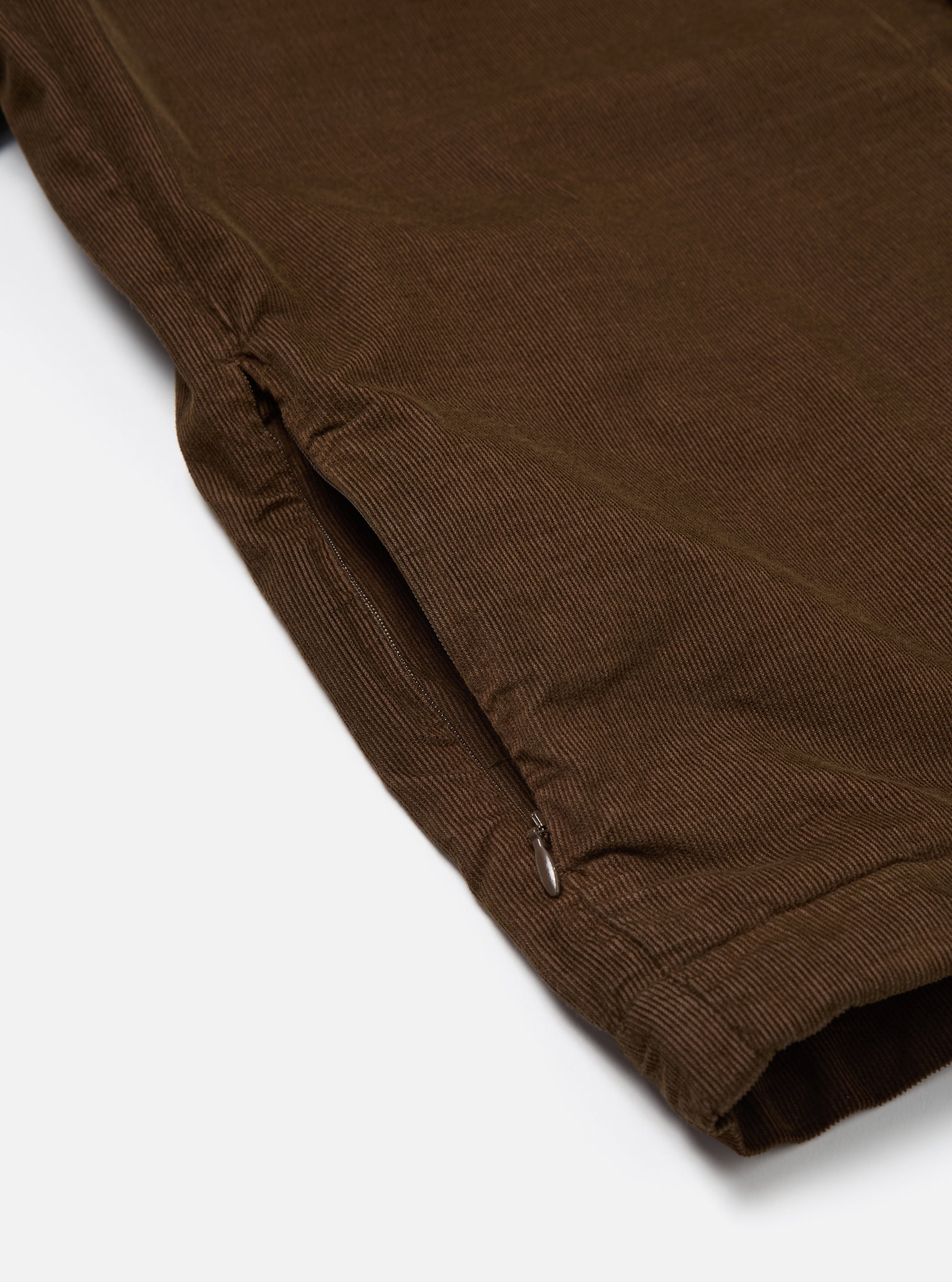 Close-up of the Khaki Summer Cord Tech Overshirt showing the corduroy texture and a side zip pocket. The overshirt is laid on a white surface.