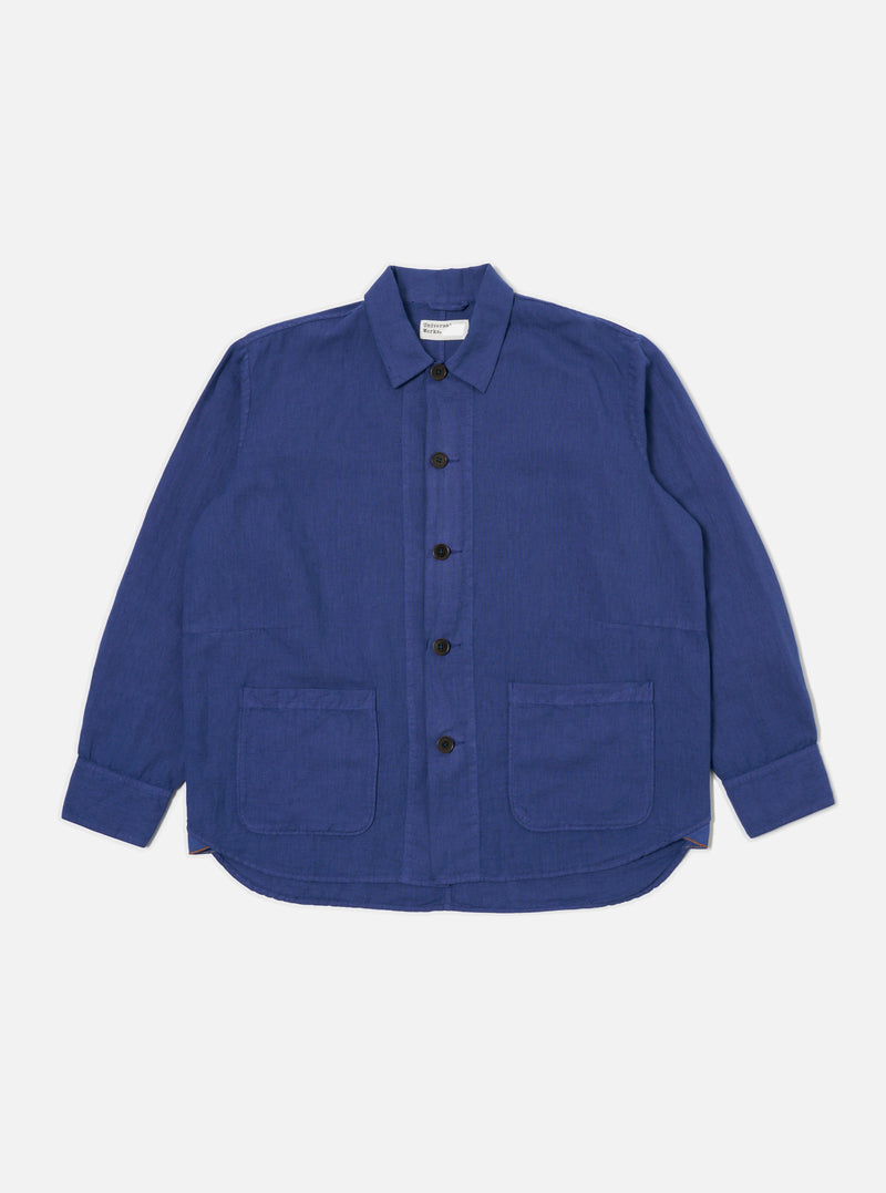 The Blue Linen Cotton Shirting Travail Overshirt is displayed on a white background. The blue overshirt features a button-down front and two front pockets.