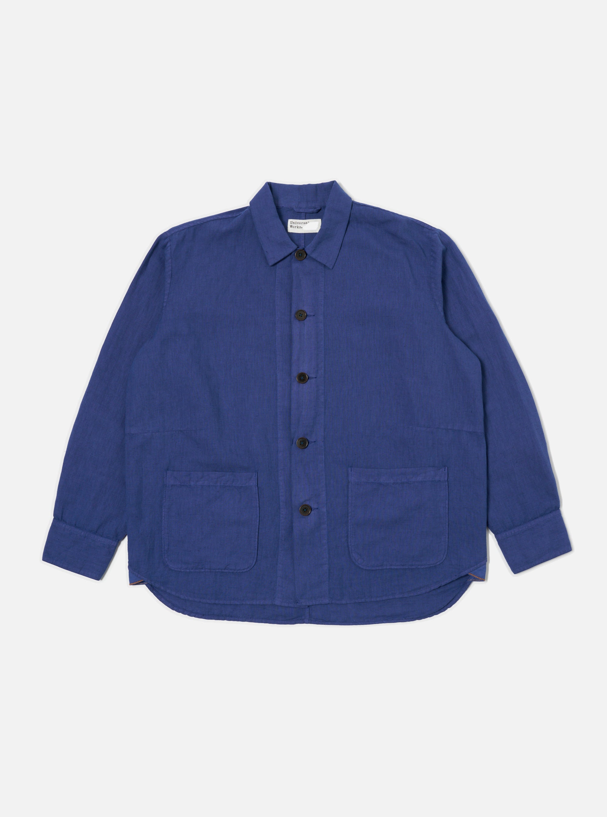 The Blue Linen Cotton Shirting Travail Overshirt is displayed on a white background. The blue overshirt features a button-down front and two front pockets.