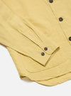 Close-up of the Lemon Linen Cotton Shirting Travail Overshirt on a white surface. Shows the sleeve, buttons, and pocket detail of the lemon-colored linen cotton shirt.