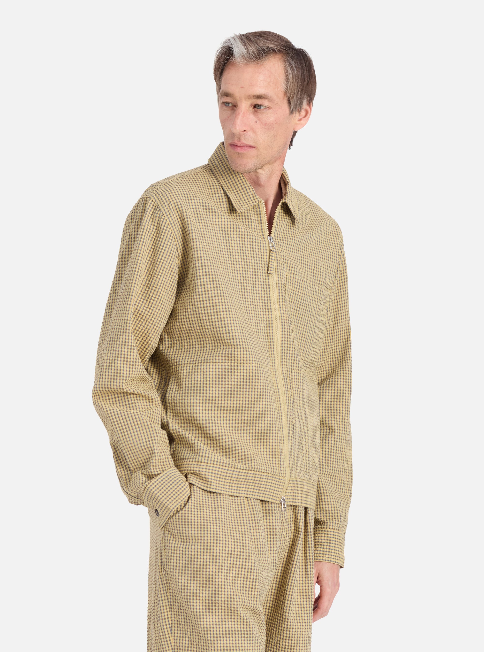 A model poses in a Yellow Japanese Seersucker Zip Uniform Jacket against a white background. The jacket is a light yellow with a subtle checkered pattern and a zip front.