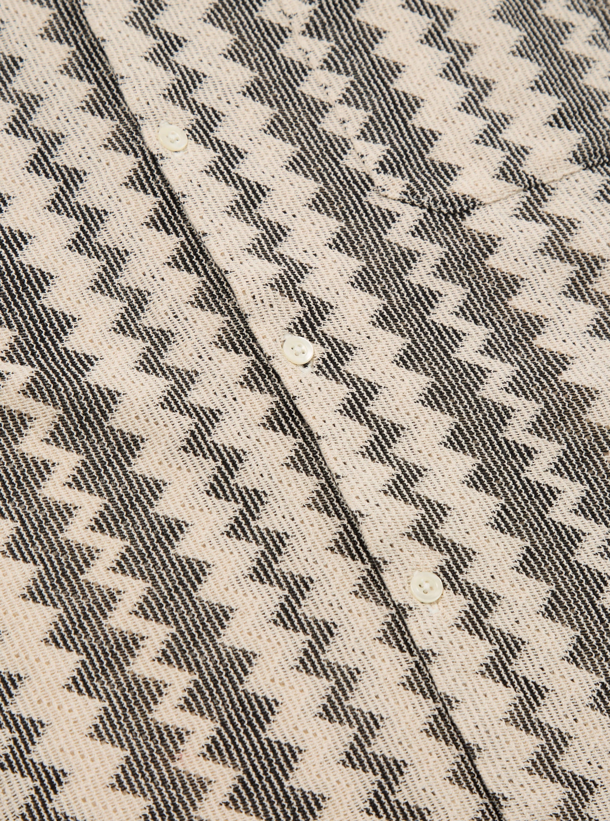Close-up of the Charcoal Cotton Lattice Road Shirt. The shirt has a charcoal lattice pattern on a cream cotton fabric. White buttons are visible.