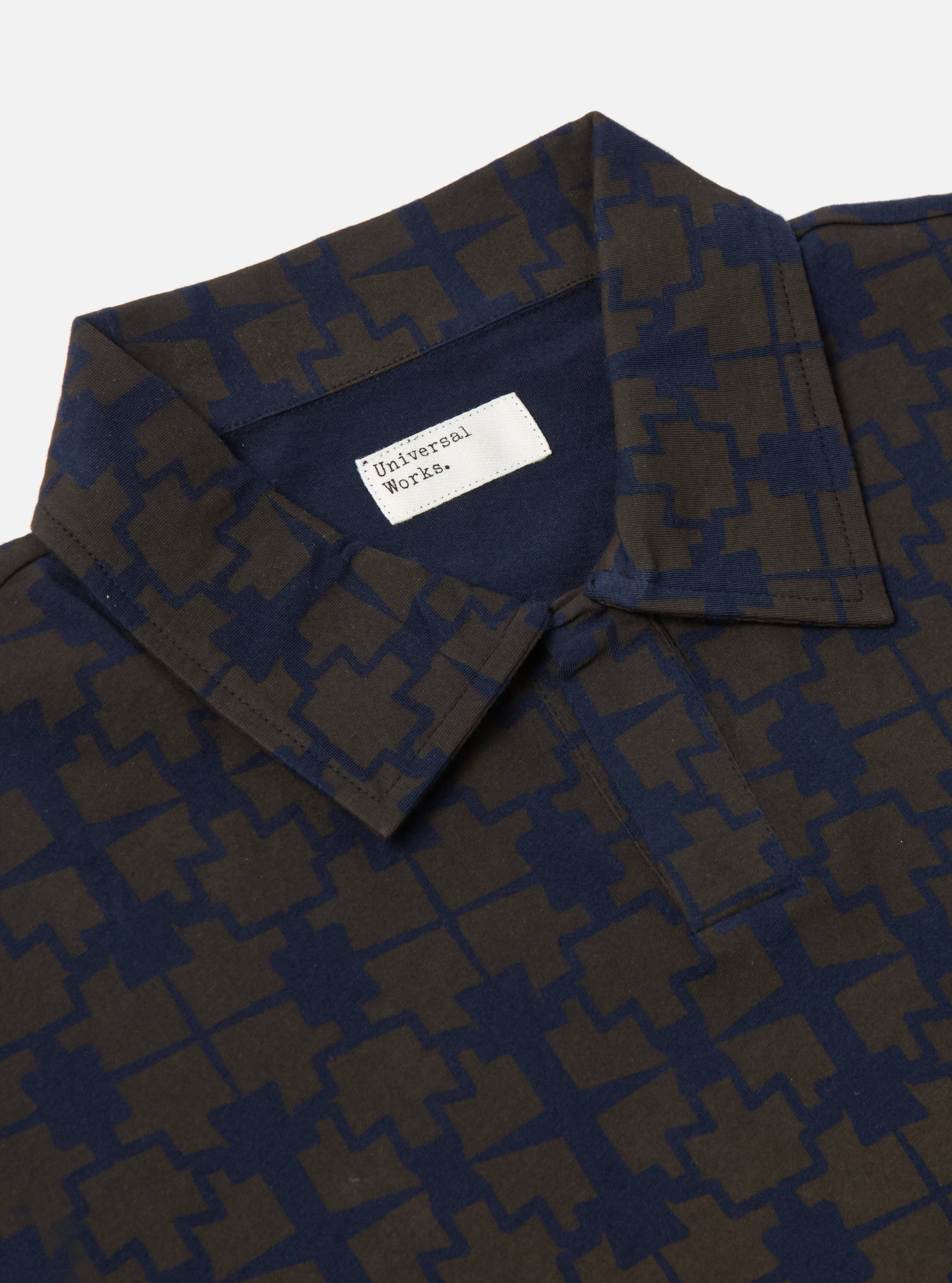Close-up of the Navy/Brown Mitla Print Jersey Newlyn Polo on a plain background. The polo features a unique geometric pattern and a classic collar.