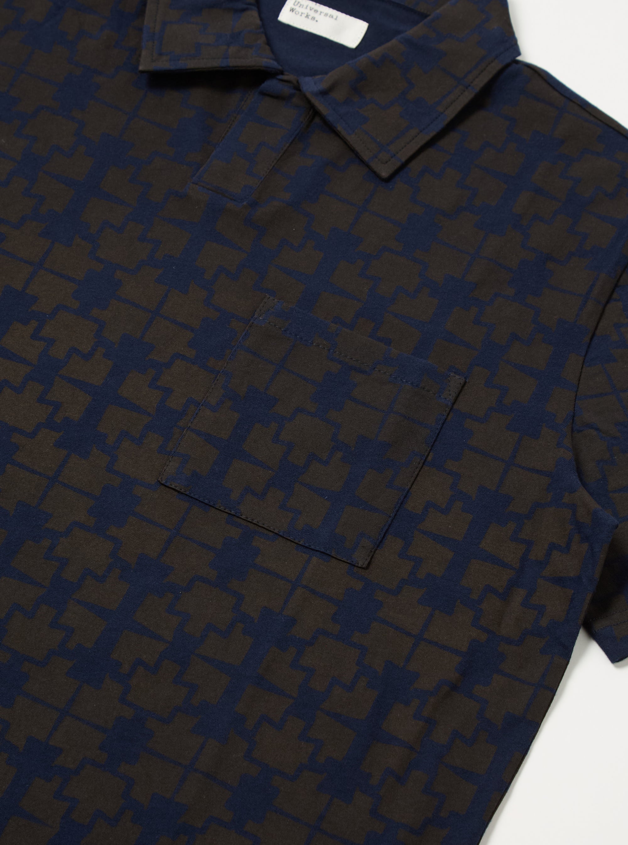 Close-up of the Navy/Brown Mitla Print Jersey Newlyn Polo, showcasing the unique pattern and jersey material. The polo is displayed on a flat surface.