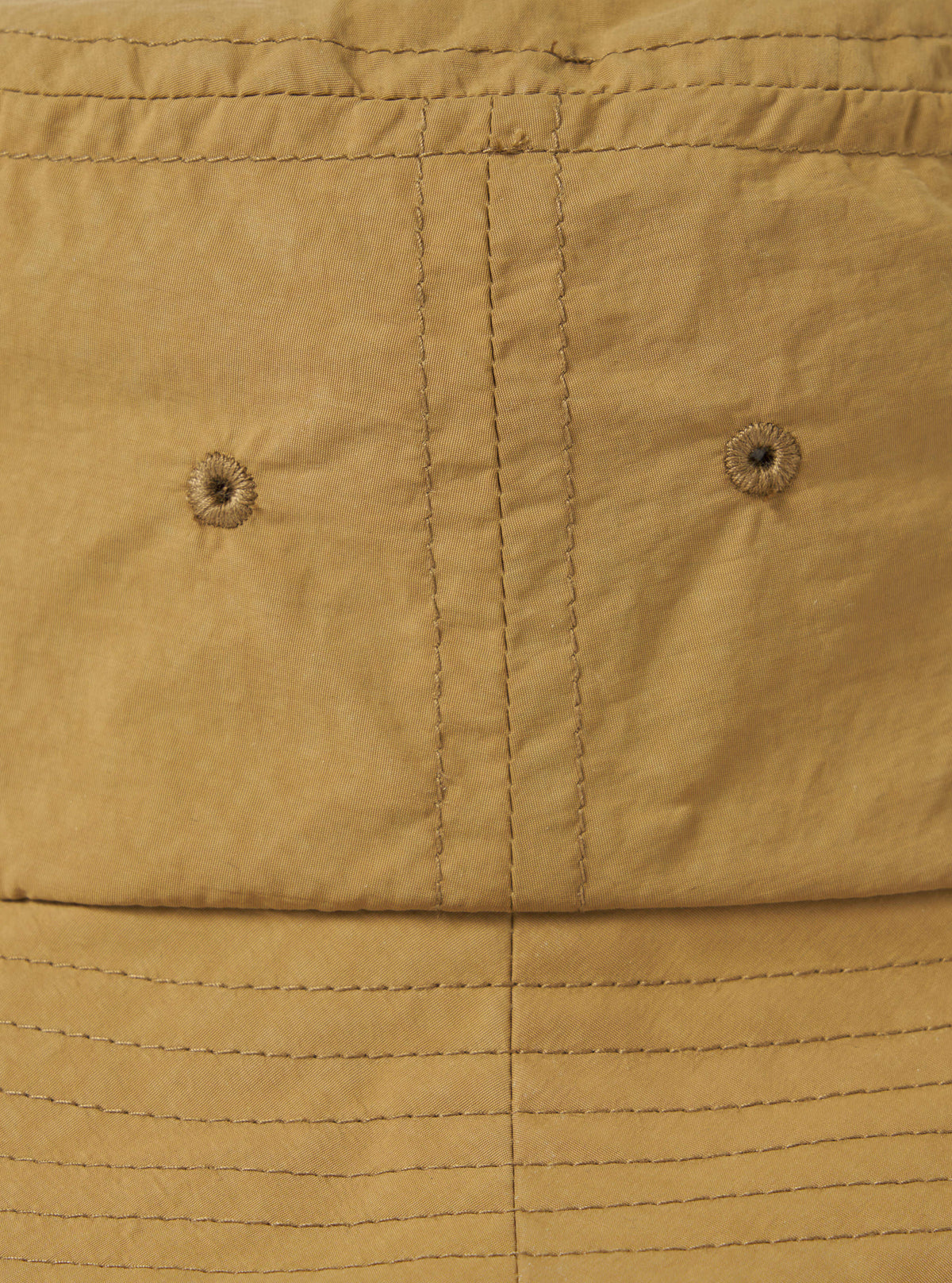 Close-up of the Dark Sand Peach Recycled Nylon Beach Hat. The hat is peach-colored with visible stitching and ventilation holes. The background is a plain white surface.