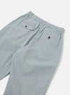 Close-up of the back of Indigo Reworked Jean Cloth Oxford Pant in light blue. Features an elastic waistband and buttoned pockets, laid on a white surface.