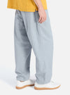 Model wears Indigo Reworked Jean Cloth Oxford Pant, light blue denim, in a studio shot against a white backdrop. The pants have a loose, relaxed fit and are paired with white sneakers.