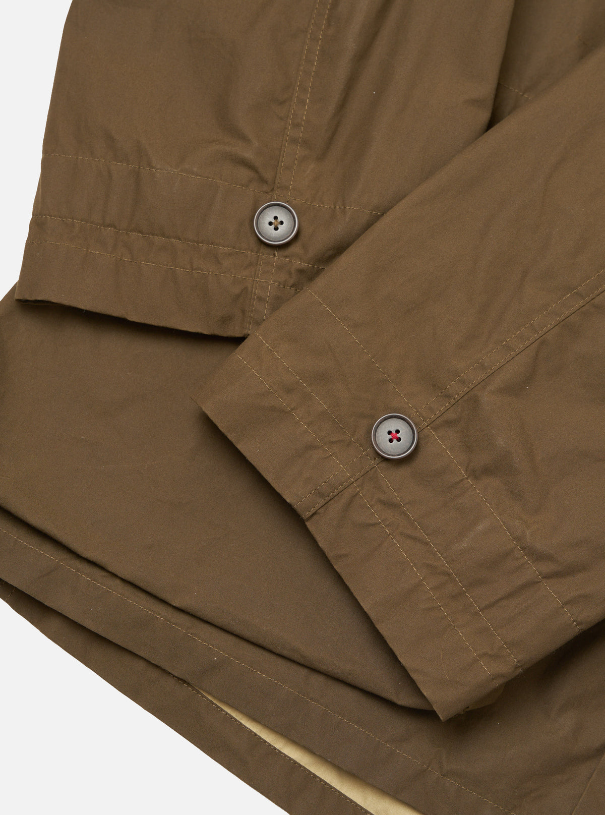 Close-up of the brown British Wax Cotton Boston Parka showing the fabric texture, button details, and stitching on a white background.