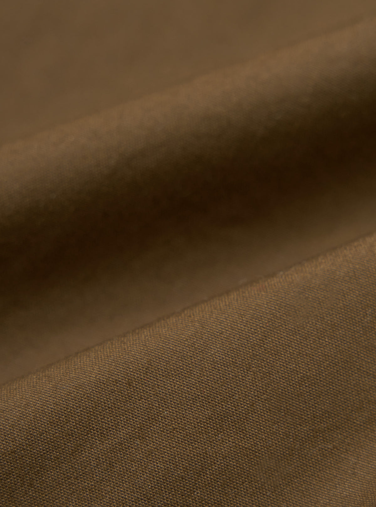 Close-up of the brown British wax cotton Boston Parka fabric. The durable material has a subtle texture. Ideal for a stylish, weather-resistant coat.
