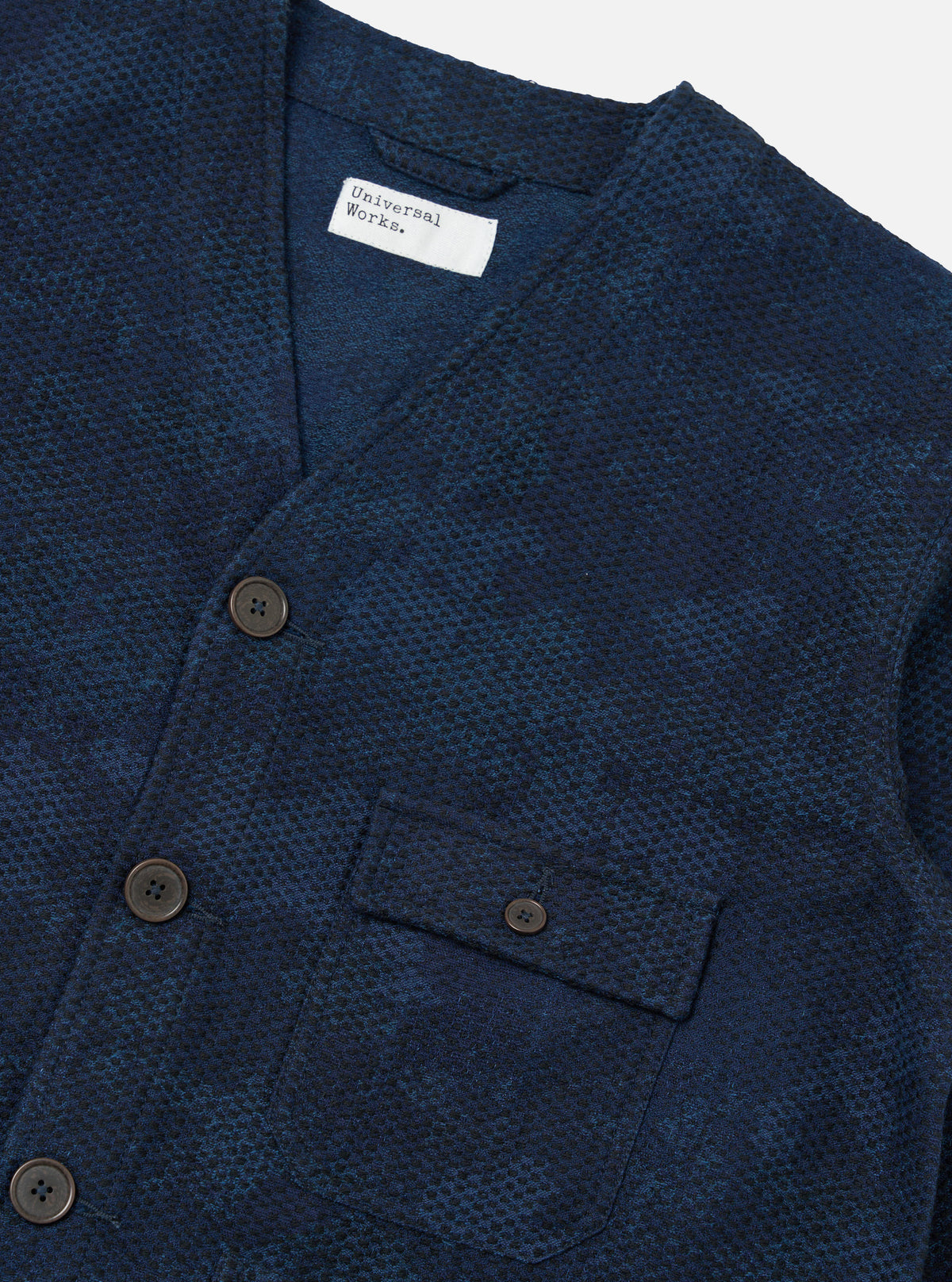 Close-up of the Black/Indigo Denim Camo Cabin Jacket on a white surface. The jacket features a button-up design and a small pocket. The camo pattern is subtle and stylish.
