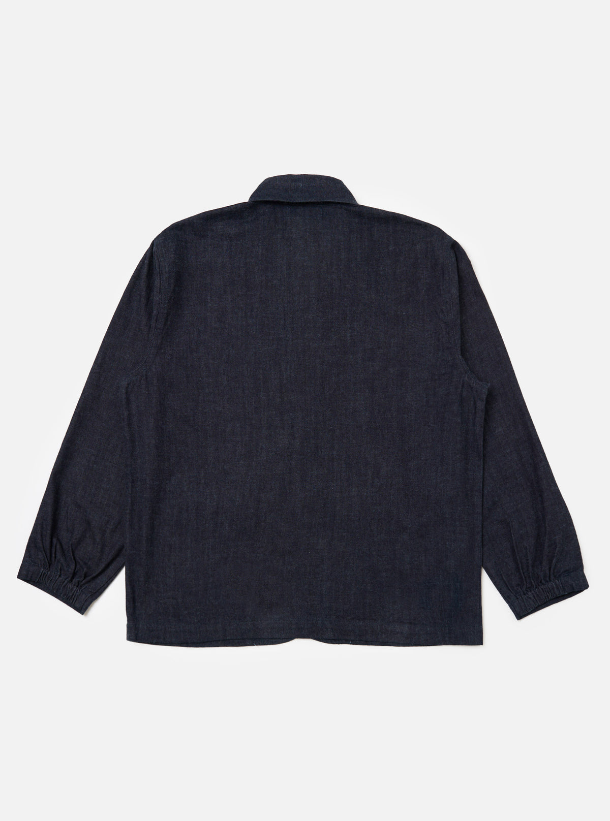 Back view of the Indigo Brushed Denim Labour Jacket on a white background. The jacket is a dark indigo color and has long sleeves with elasticated cuffs.