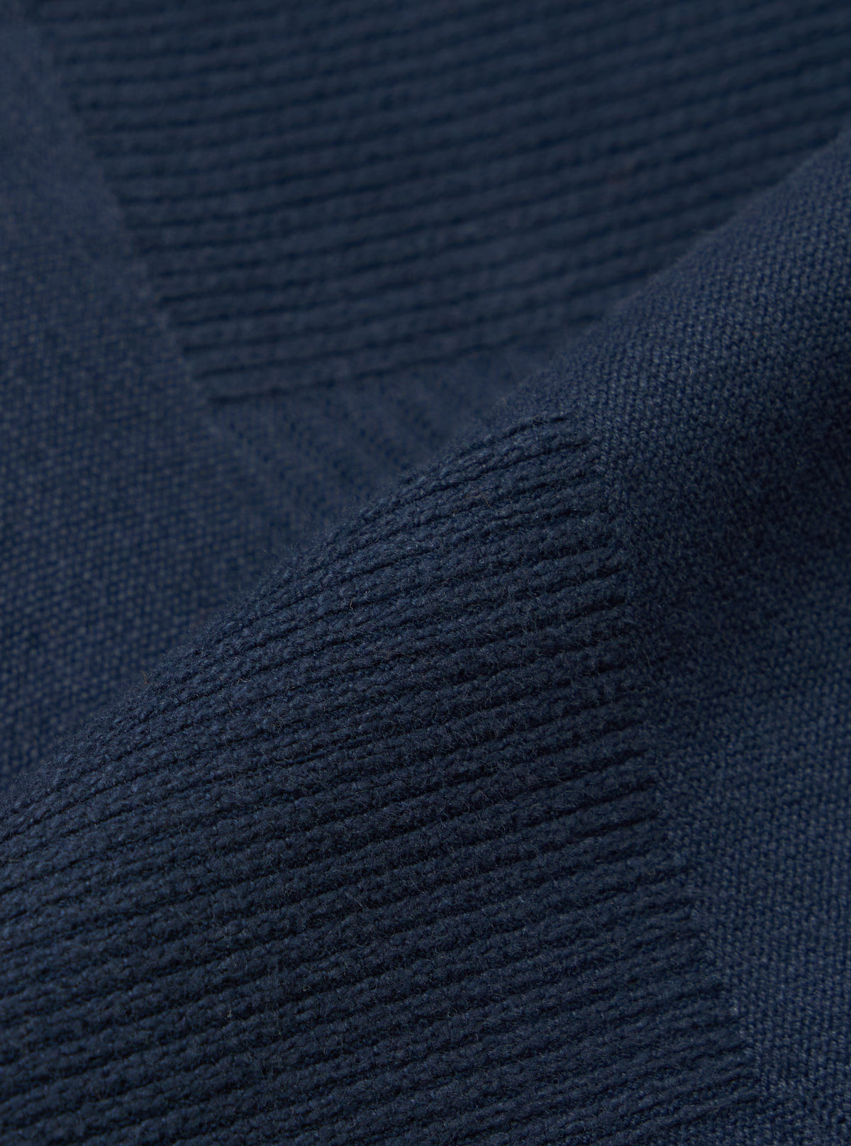 Close-up of the dark navy patchwork weave cotton labour jacket, showcasing the fabric's texture and color in a studio setting.