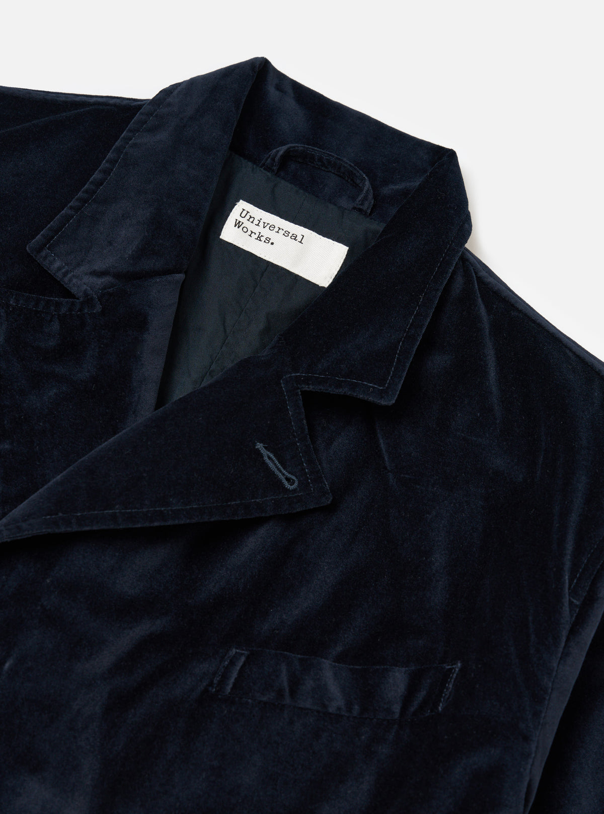 Close-up of the Navy Velveteen Manor Jacket on a white background. The jacket is a rich navy color and has a soft, velvety texture. Features a classic collar and button closure.