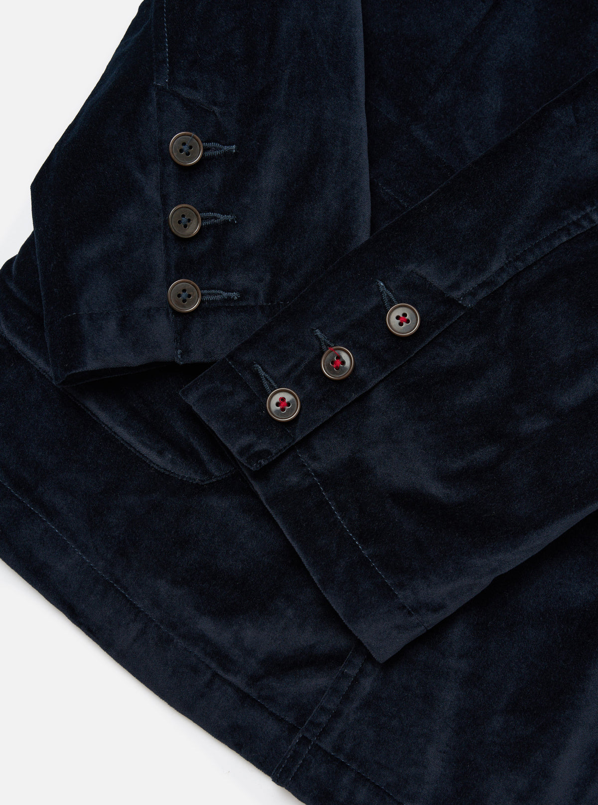 Close-up of the navy velveteen Manor Jacket on a white surface. Shows the jacket's buttons and soft texture. The jacket is neatly folded, highlighting its tailored fit.