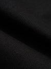 Close-up of the Black Works Twill Rose Bowl Jacket material. The black twill fabric is folded, showing the texture and weave. Dark, moody lighting.