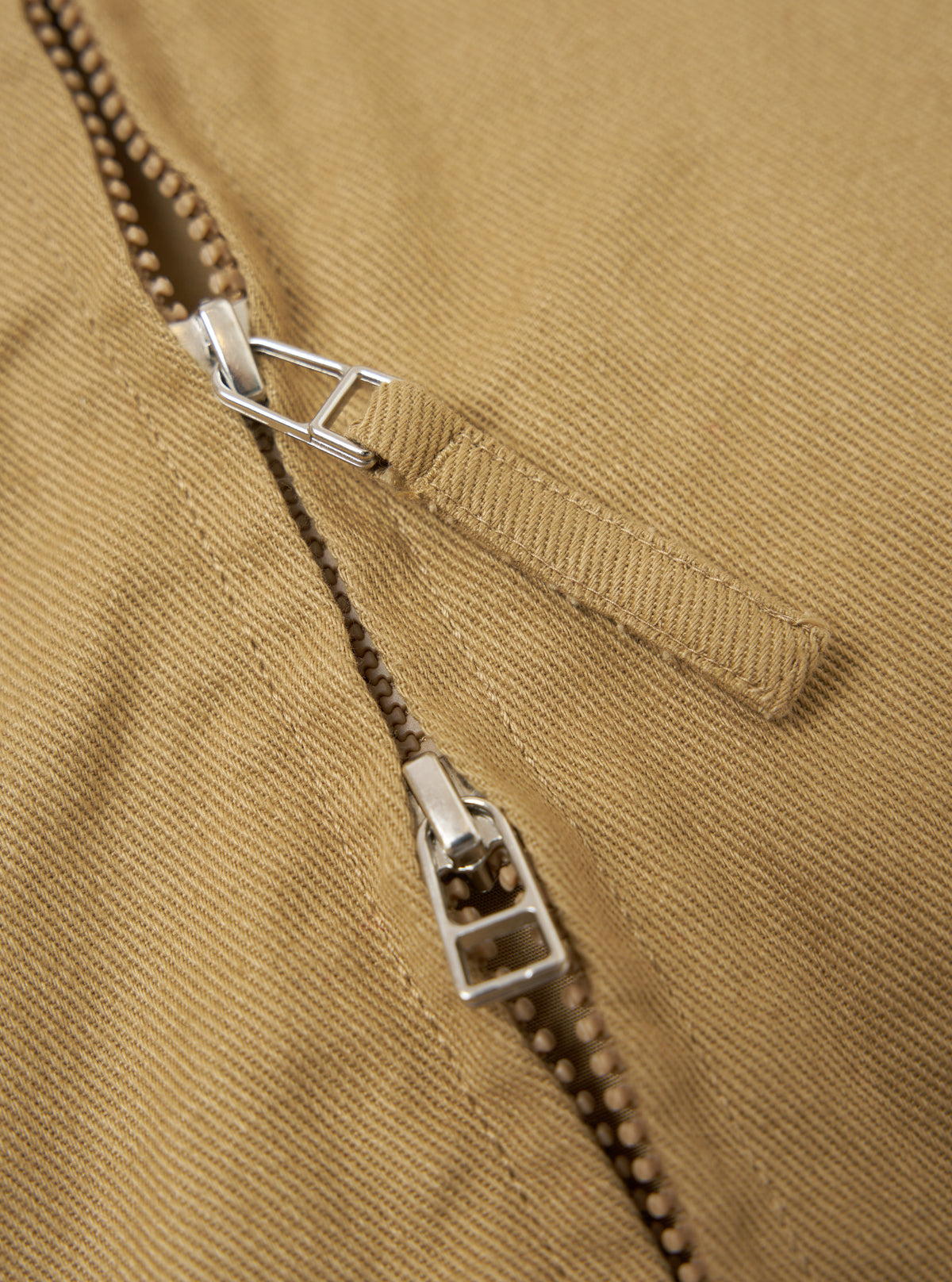 Close-up of the Khaki Works Twill Rose Bowl Jacket, showcasing the zipper detail. The jacket is made of khaki twill fabric. The background is a plain white surface.
