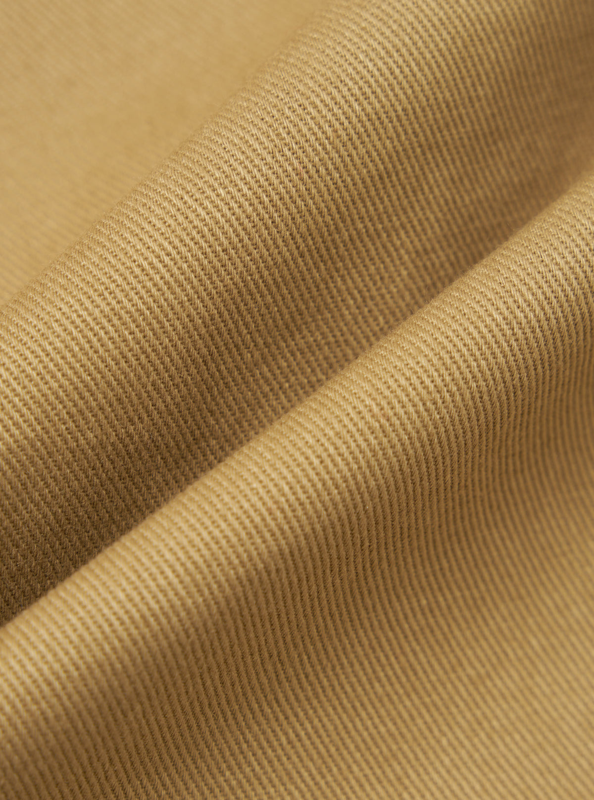 Close-up of the twill fabric of the Khaki Works Twill Rose Bowl Jacket. The material is a light brown color and has a subtle texture. The fabric is draped to show its quality.