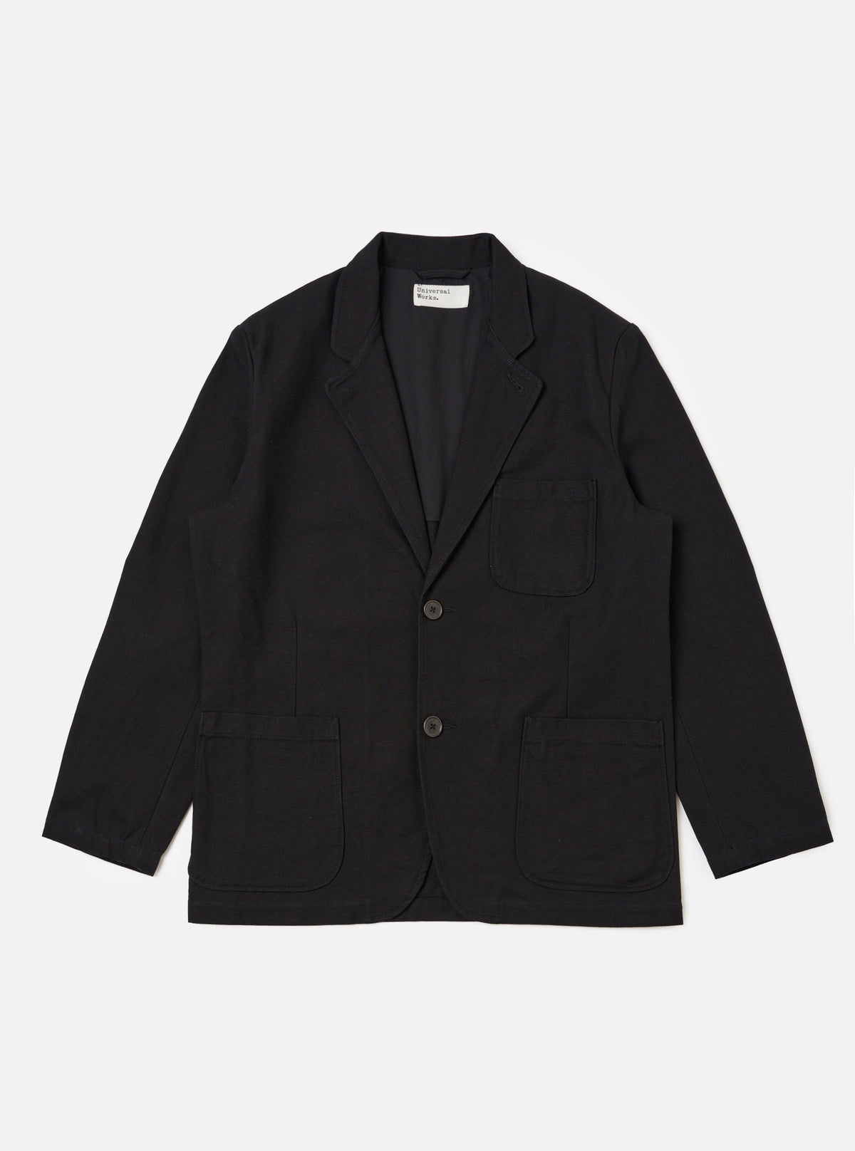 The Black Organic Canvas Two Button Jacket is laid flat on a white background. The jacket is a dark black color and has two pockets on either side.