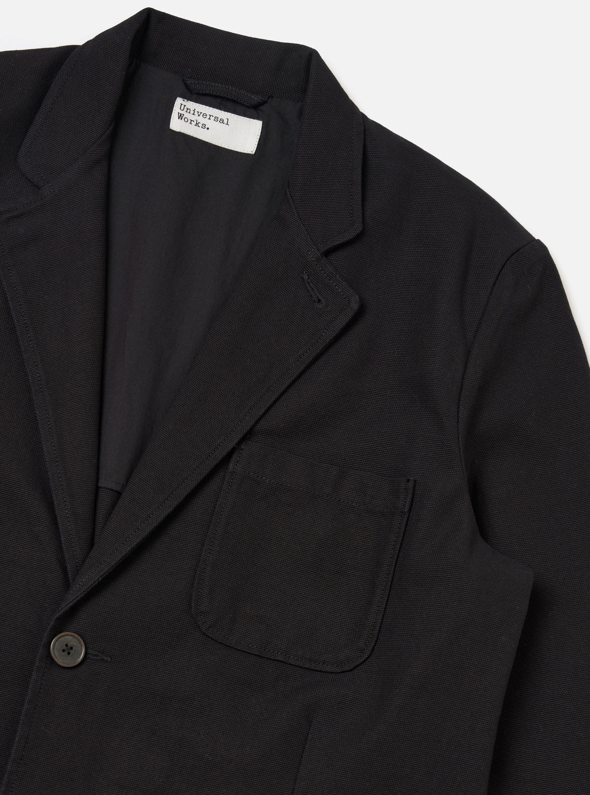 Close-up of the Black Organic Canvas Two Button Jacket on a white background. The jacket is made of black canvas and has a two-button closure.