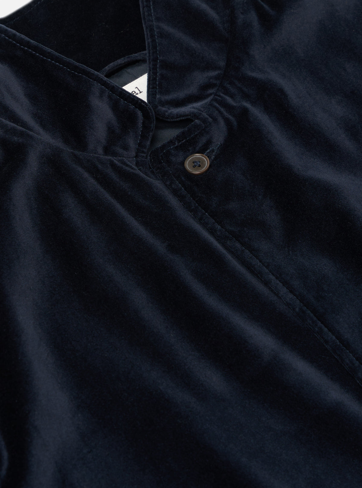 Close-up of the navy velveteen two button jacket. The soft, luxurious fabric is highlighted in the studio lighting. The jacket features a classic, tailored fit.