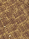Close-up of the Khaki Patch Check Twill Fatigue Shirt. The shirt features a brown and khaki check pattern, a chest pocket, and button closure. Shot on a flat surface.