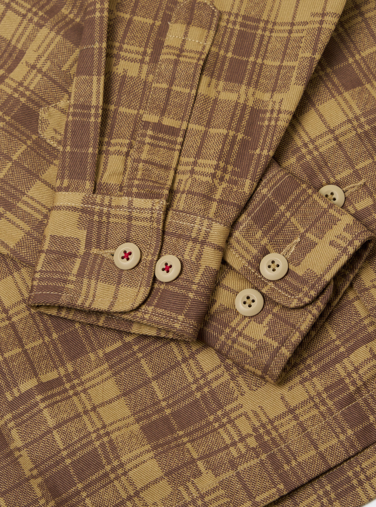 Close-up of the Khaki Patch Check Twill Fatigue Shirt. The shirt features a brown and khaki check pattern, twill fabric, and buttoned cuffs. The background is a plain white surface.