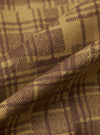 Close-up of the Khaki Patch Check Twill Fatigue Shirt fabric. The twill weave shows a khaki and brown check pattern. The fabric is draped to show texture.