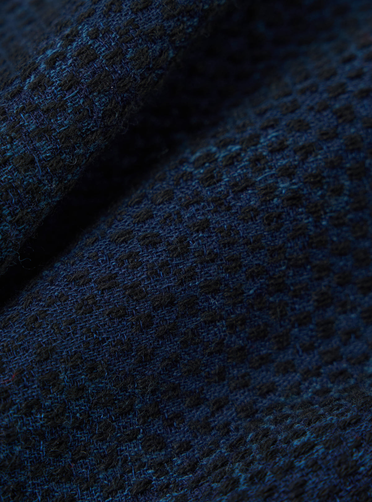 Close-up of the Black/Indigo Denim Camo 4 Pocket Gilet fabric. The denim has a subtle camo pattern in black and indigo. The texture of the fabric is visible.