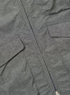 Close-up of the Charcoal Organic Chambray Parachute Liner Gilet, showcasing the fabric texture, pockets, and zipper detail on a flat surface.