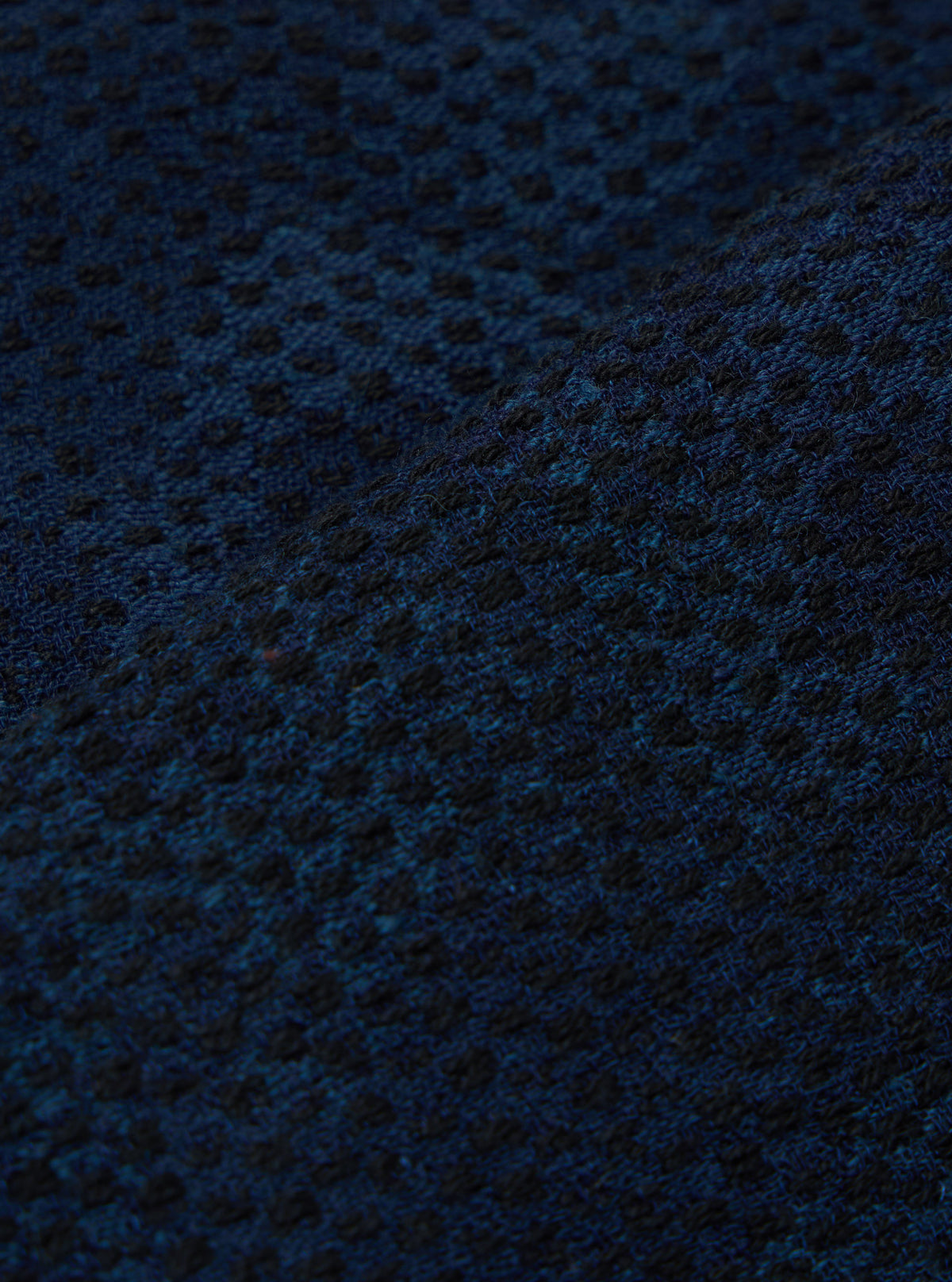 Close-up of the Black/Indigo Denim Camo Braga Pant fabric. The material has a subtle camo pattern in black and indigo. The fabric is textured and folded.