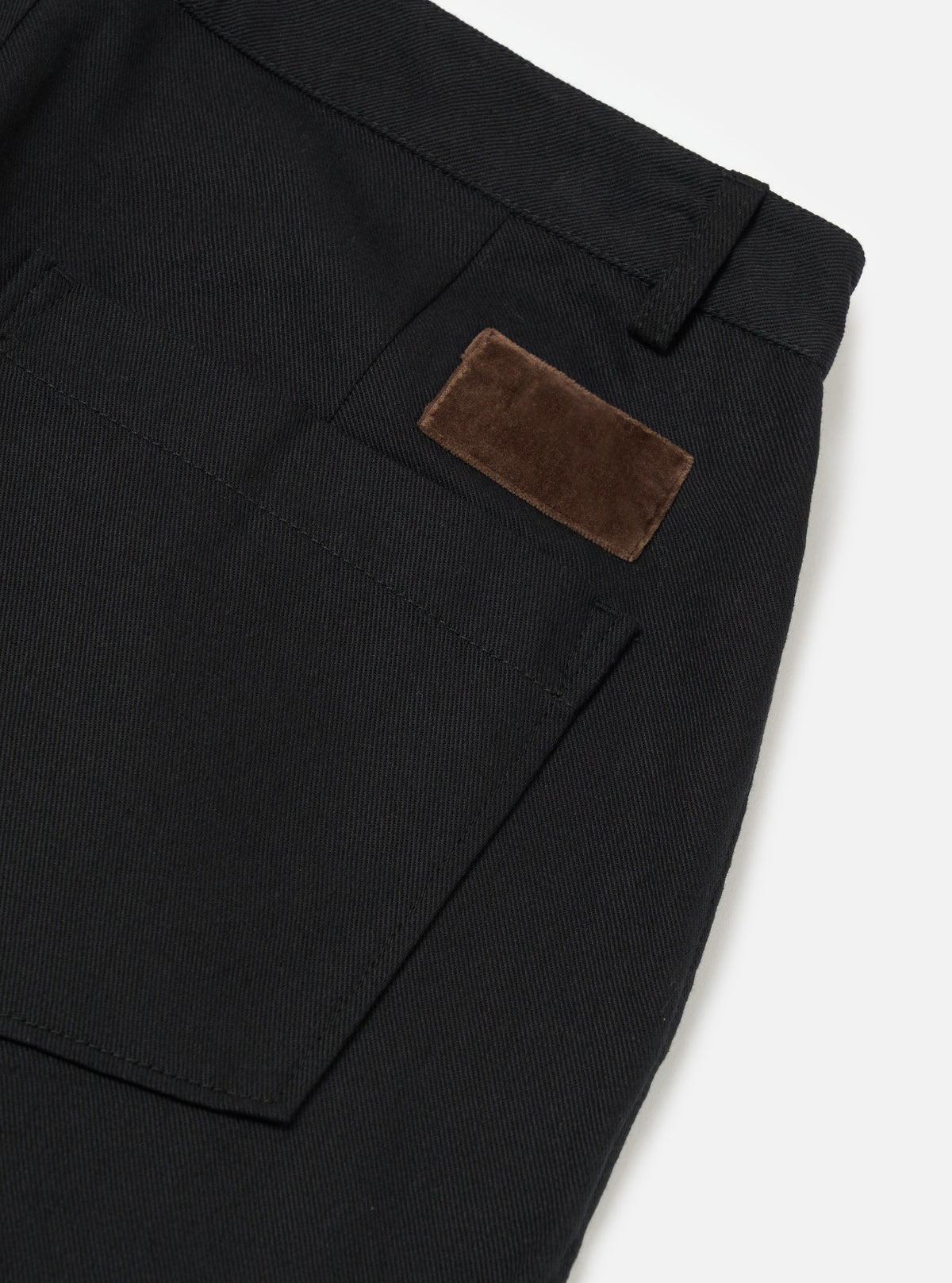 Close-up of the Black Works Twill Duke Pant, showcasing the black twill fabric, pocket detail, and brown patch on a white background.