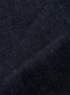 Close-up of indigo brushed denim military chino fabric. The dark blue material is textured and folded, showcasing its weave. Studio shot.