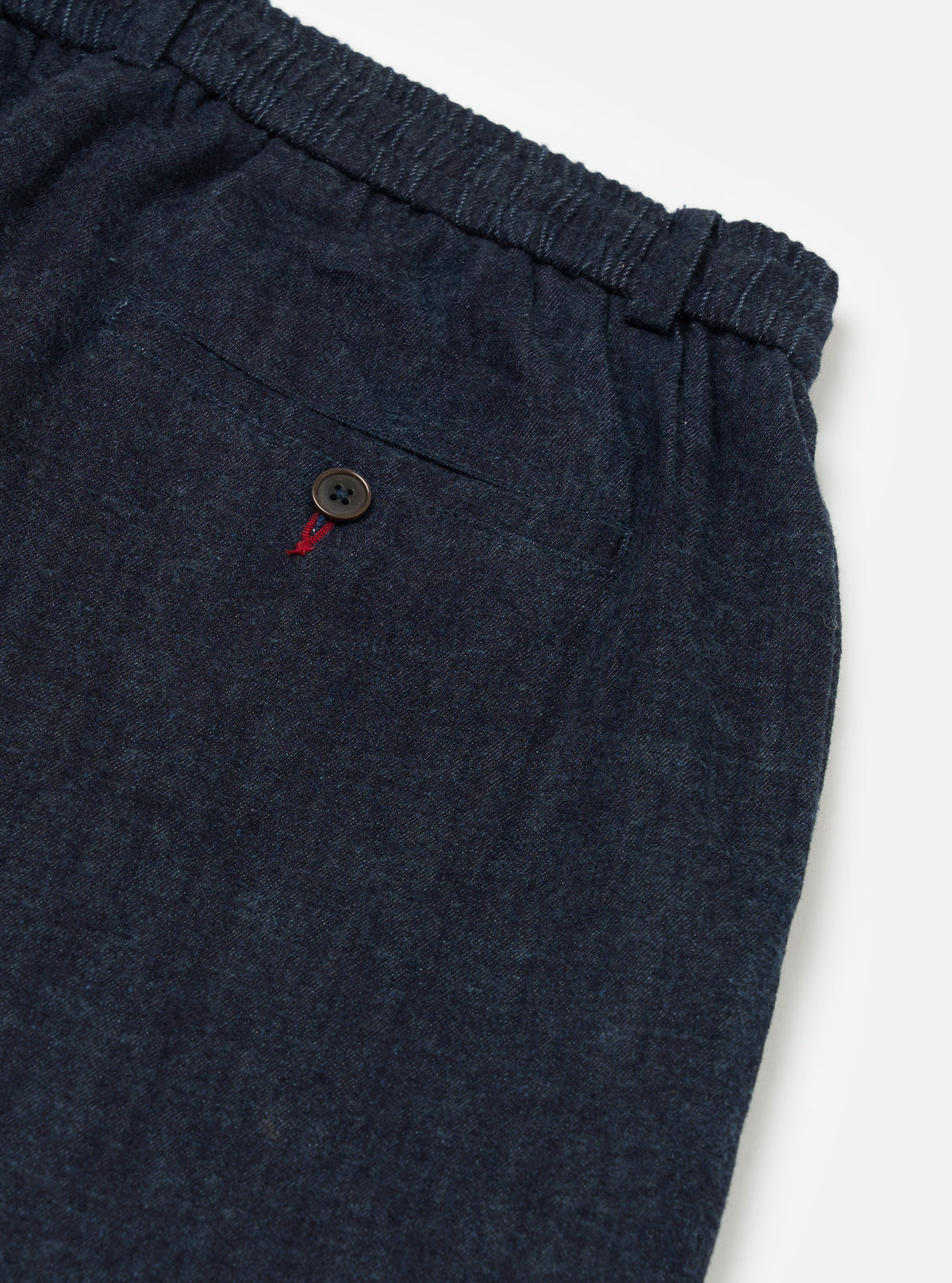 Close-up of the Indigo Brushed Denim Oxford Pant showing the elastic waistband, buttoned pocket, and brushed denim texture on a white background.